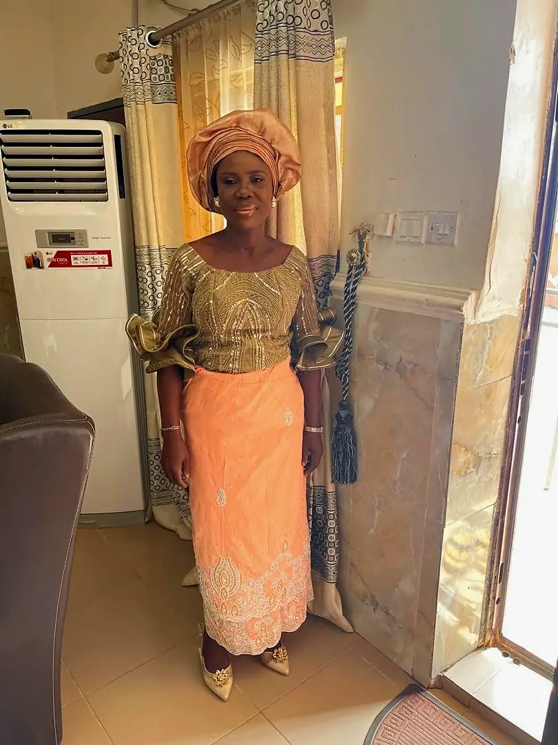 The co-founder of Caritana Global Limited, in a gold and peach outfit with a matching head tie