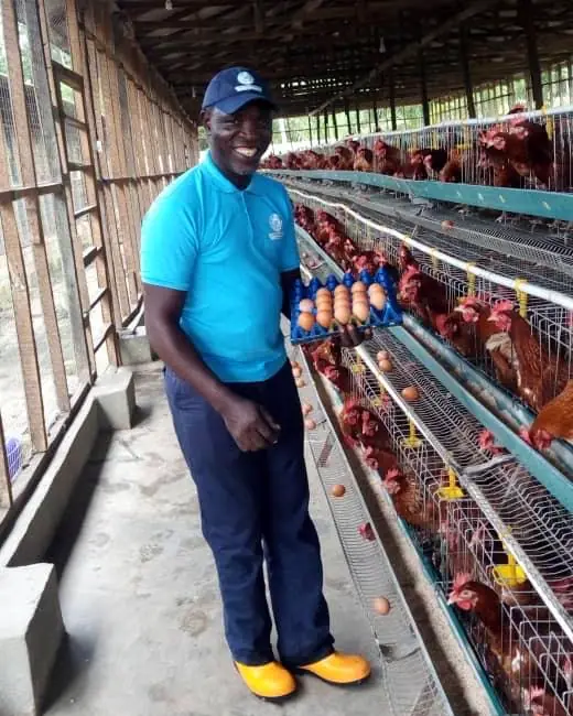 A smiling team member in a turquoise polo with a tray of eggs
